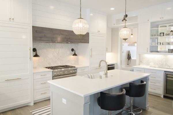 White shaker-style kitchen with an island, marble-effect worktops and pendant lights