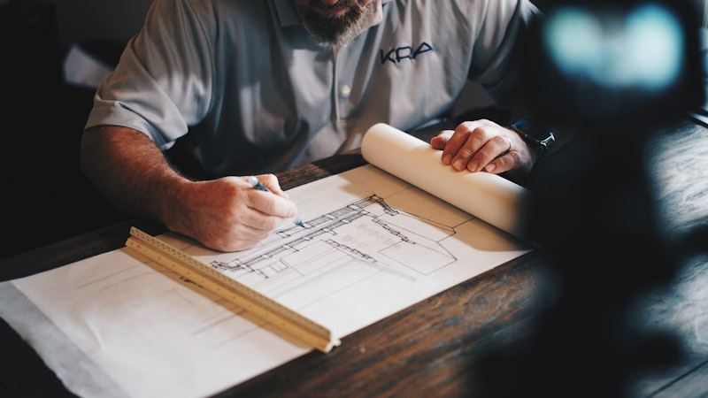 Floor plans being marked up with a pencil and ruler on a desk